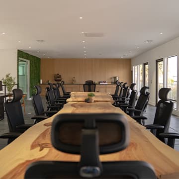 Conference Room III: long dark wood table with black ergonomic chairs beneath a sculptural pendant light