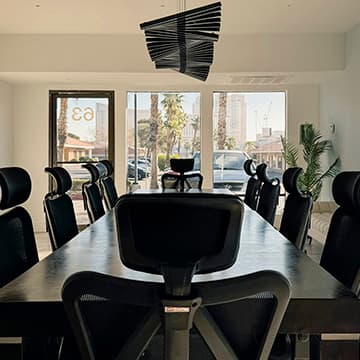 Long dark wood conference table with black ergonomic chairs beneath a sculptural pendant light