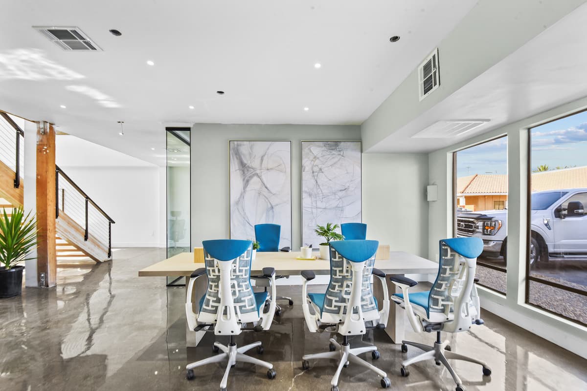 Meeting room with a light wood table, blue-and-white ergonomic chairs and two abstract line drawings
