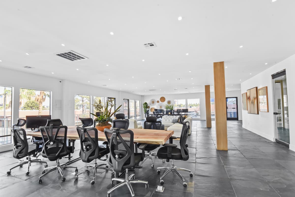Upstairs open workspace with a live-edge table, black mesh chairs, slate floors and a wood column