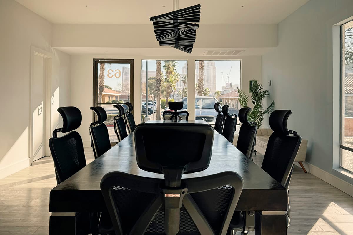 Conference Room III: long dark wood table with black ergonomic chairs and a pendant light, facing windows onto the Strip