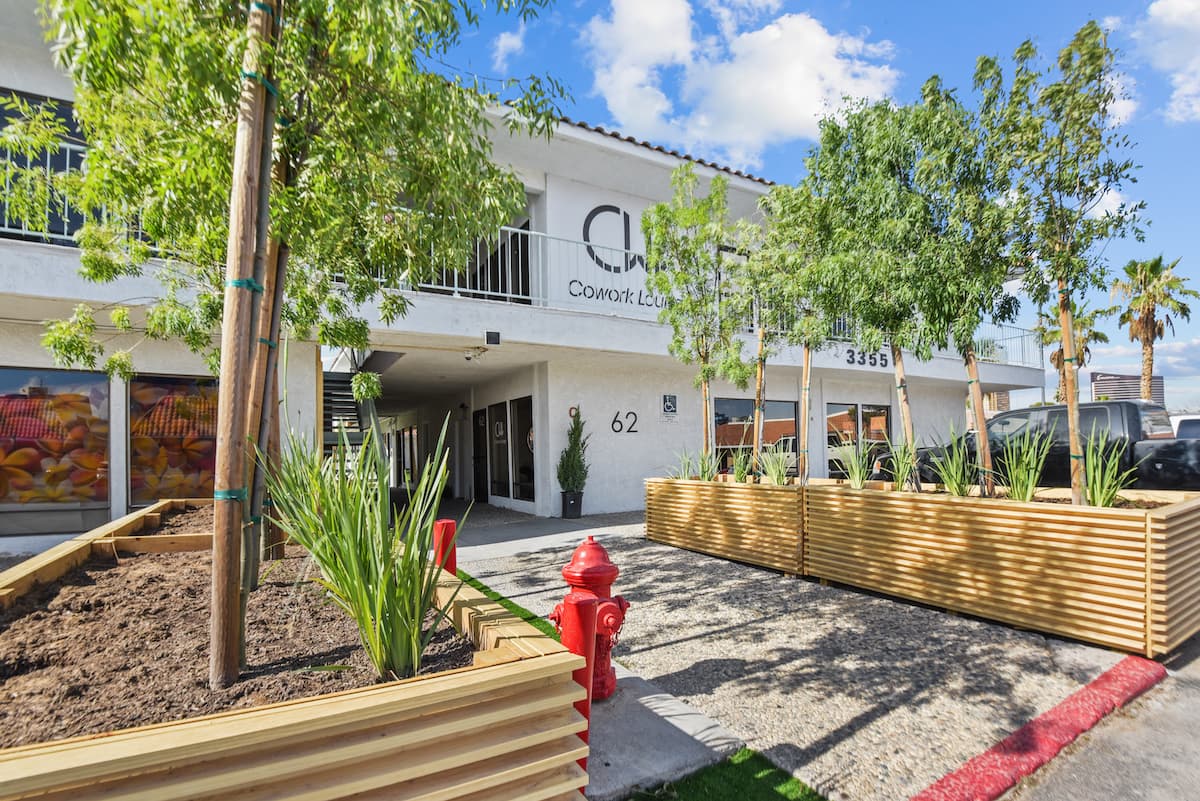 Cowork Lounge building exterior with the CWL sign, cedar planters, young trees and a red fire hydrant