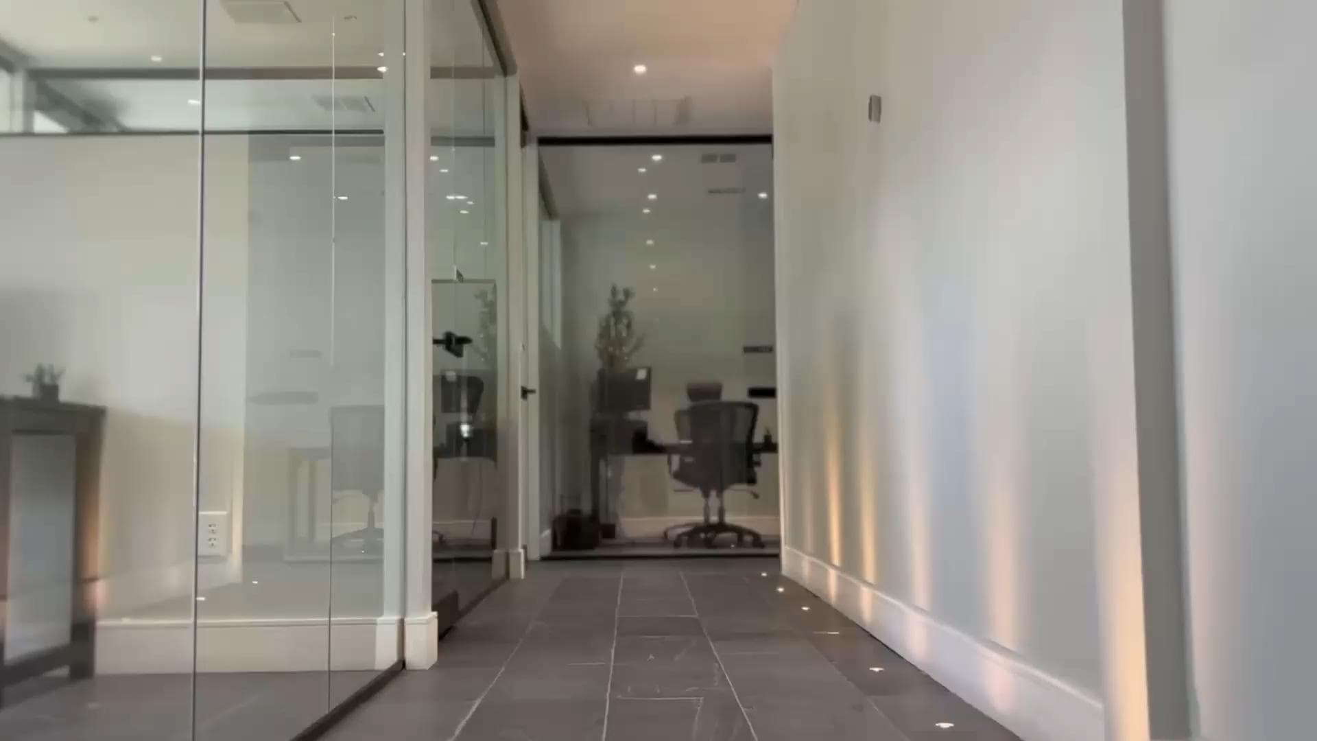 Hallway lined with glass-walled private offices and a slate tile floor